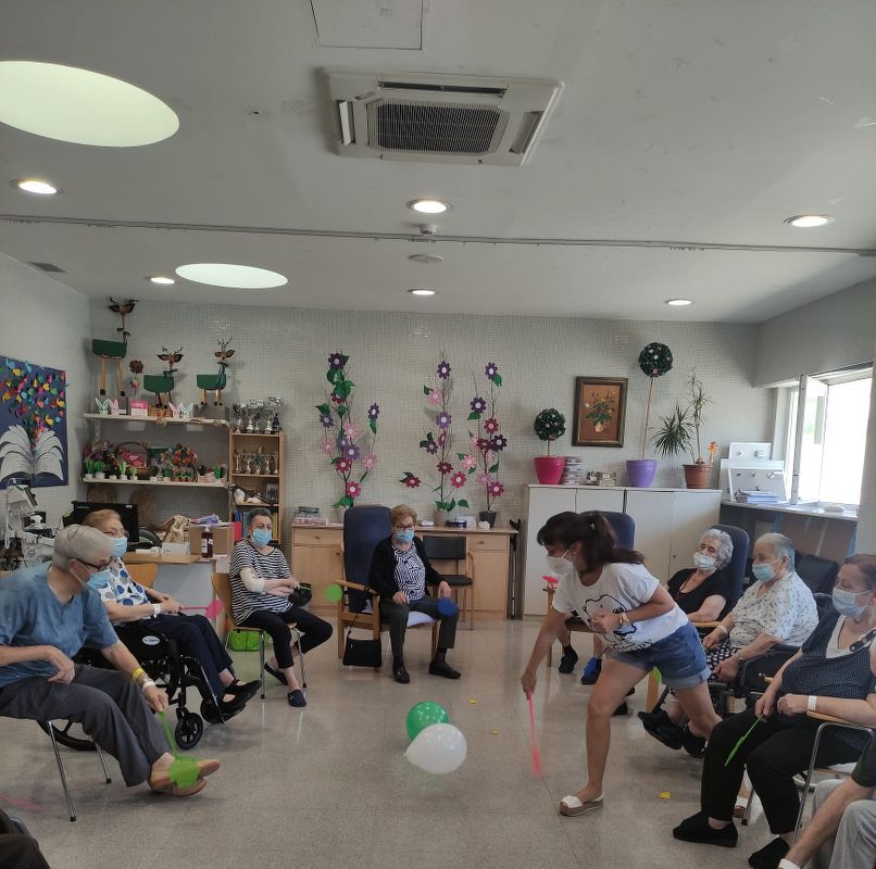 Taller musical i cognitiu Hospital de Dia i Unitat Sociosanitaria Hospital Comarcal de Móra d’Ebre Gent gran jugant amb globus en un taller